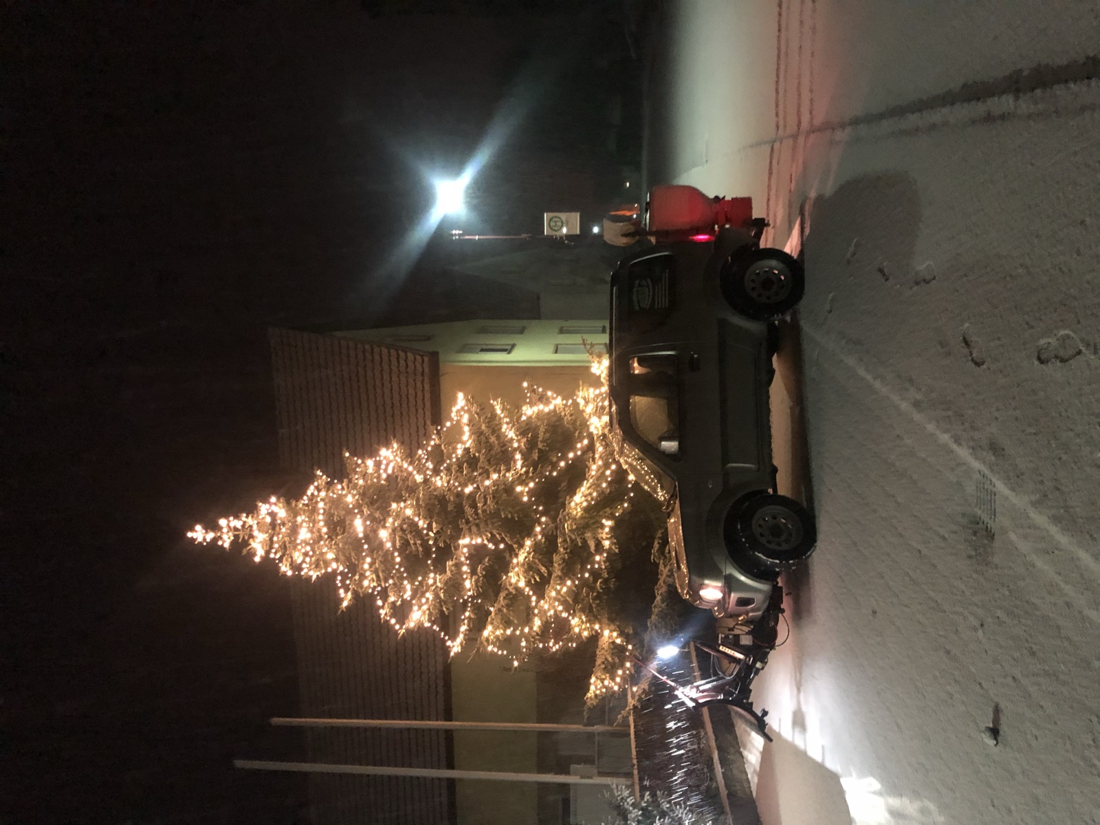 Winterdienst-Fahrzeug mit Schneepflug bei Nacht im Schnee